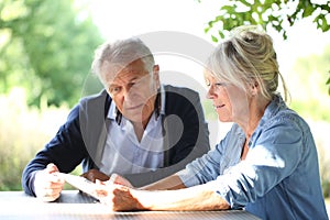 Modern senior couple using tablet on terrace garden