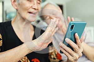 Modern senior grandmother using mobile phone,looking at cell phone screen,Waving her hands,Say Hi,talking to family while online