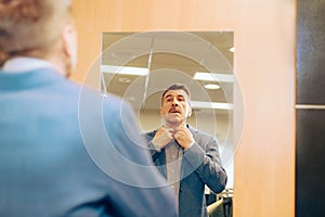 Modern senior in a suit in jeans and sneakers near the mirror. man trying on clothes in a boutique