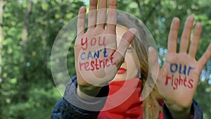 Modern serious girl with long dreadlocks in red scarf is showing hands with written slogan `You can`t restrict our