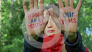 Modern serious girl with long dreadlocks in red scarf is showing hands with written slogan `You can`t restrict our