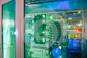 A modern server room is located behind a glass wall. Datacenter Servers running