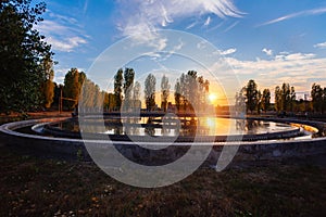 Modern sewage treatment plant. Round wastewater purification tank at sunset