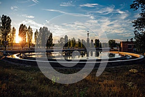 Modern sewage treatment plant. Round wastewater purification tank at sunset