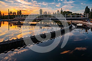 Modern sewage treatment plant. Round wastewater purification tanks at sunset