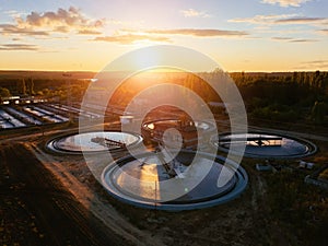 Modern sewage treatment plant. Round wastewater purification tanks at sunset, aerial view