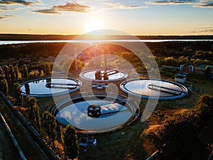 Modern sewage treatment plant. Round wastewater purification tanks at sunset, aerial view