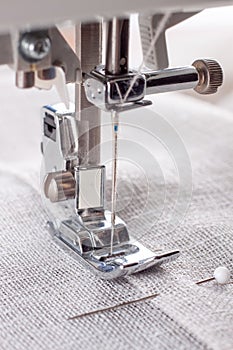 Modern sewing machine presser foot with linen fabric and thread, closeup