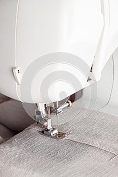 Modern sewing machine presser foot with linen fabric and thread, closeup