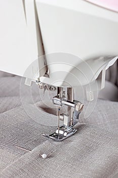 Modern sewing machine presser foot with linen fabric and thread, closeup