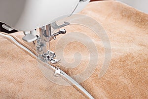 Modern sewing machine special presser foot with beige fabric and zipper, closeup
