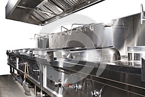 Modern shiny and clean kitchen with stainless steel kitchenware, stove, exhaust, and equipment for restaurant-scale cooking