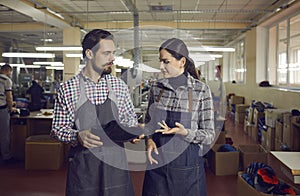 Modern shoemaking factory workers discussing design of new suede footwear collection