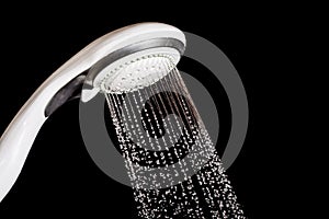 Modern shower head with running water isolated on black