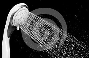 Modern shower head with running water isolated on black