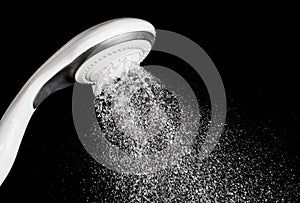 Modern shower head with water isolated on black backgr