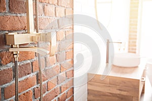 Modern shower system copper color for bathroom in loft style, brick wall. Sunlight window