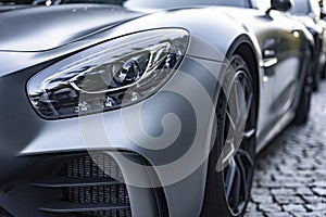 Modern silver car parking on the road. Close up. Headlights detail.