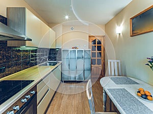 Modern simple interior of kitchen. White table and chairs. Sink and oven. Wooden door.