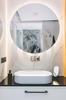 Modern sink and round mirror with led light in a luxury bathroom