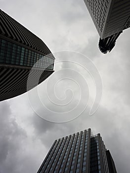 Modern skyscraper against a gray gloomy sky. Looking up