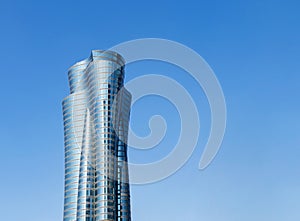 Modern skyscraper with glass facade. Qatar International Islamic Bank Headquarters Tower on blue background, copyspace