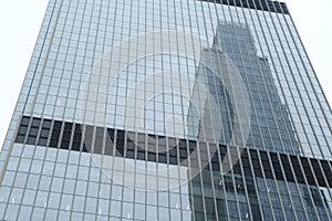 Modern skyscraper with glass windows. From below of contemporary tall building with reflection of skyscraper.