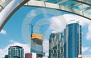 Modern skyscraper high rise buildings under construction with cranes framed by a steel and glass arch