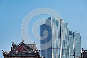 Modern skyscraper tower above traditional Chinese building