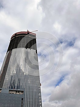 Modern skyscraper under construction with crane. From below of contemporary tall skyscraper with glass walls and with