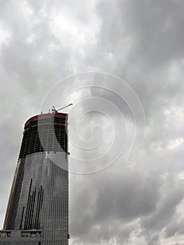 Modern skyscraper under construction with crane. From below of contemporary tall skyscraper with glass walls and with