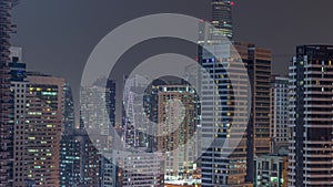 Modern skyscrapers in Dubai Marina, close up view to many illuminated windows aerial night timelapse.