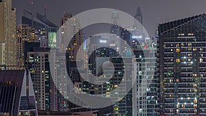 Modern skyscrapers in Dubai Marina, close up view to many illuminated windows aerial night timelapse.