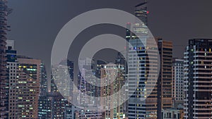 Modern skyscrapers in Dubai Marina, close up view to many illuminated windows aerial night timelapse.