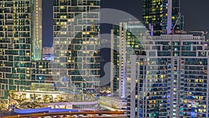 Modern skyscrapers in Dubai Marina, close up view to many illuminated windows aerial night timelapse.