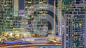 Modern skyscrapers in Dubai Marina, close up view to many illuminated windows aerial night timelapse.