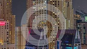 Modern skyscrapers in Dubai Marina, close up view to many illuminated windows aerial night timelapse.