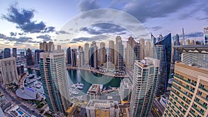 Modern skyscrapers and water channel with boats of Dubai Marina at sunset and day to night timelapse, United Arab