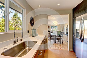 Modern small new kitchen with large sink and white countertops.