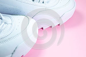 Modern sneakers on the pink background. White leather trainers on big sole with spikes. Close up