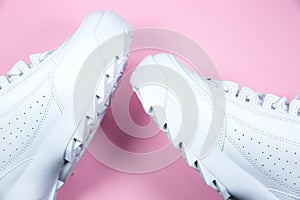 Modern sneakers on the pink background. White leather trainers on big sole with spikes. Close up