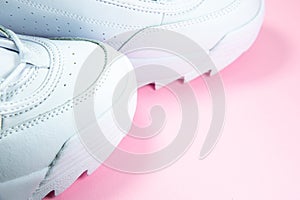 Modern sneakers on the pink background. White leather trainers on big sole with spikes. Close up