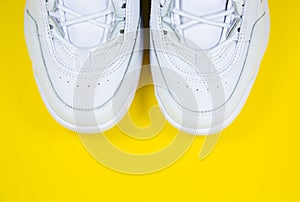 Modern sneakers on the yellow background. White leather trainers on big sole with spikes. Close up