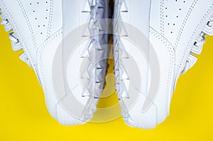 Modern sneakers on the yellow background. White leather trainers on big sole with spikes. Close up