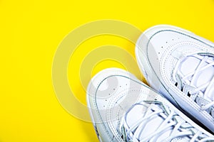 Modern sneakers on the yellow background. White leather trainers on big sole with spikes. Close up