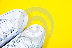 Modern sneakers on the yellow background. White leather trainers on big sole with spikes. Close up