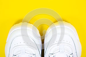 Modern sneakers on the yellow background. White leather trainers on big sole with spikes. Close up