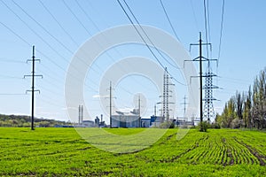 Modern soybean processing plant, agricultural Silos against green field and blue sky. Storage and drying of grains, wheat, corn,