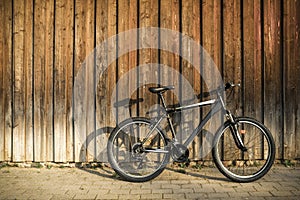 Modern sport mountain bike leaning against brown wooden wall