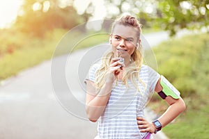 Modern sporty young woman eating energy bar after run in park